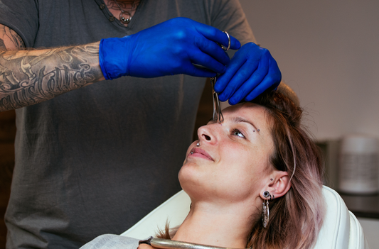 a girl laying down and getting her nose bridge pierced